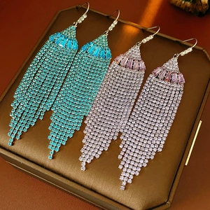 Macro view of crystal tassel fan earrings in peacock blue and light pink stone pavé