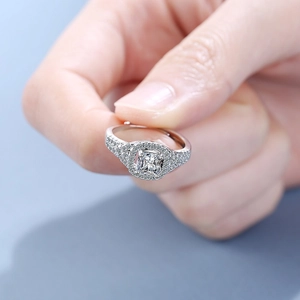 Adjustable silver ring with square zircon stone and halo setting held by hand