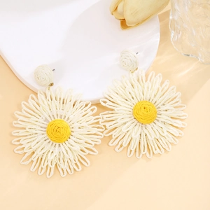 Detail of handmade raffia flower earrings with yellow centers and cream woven petals