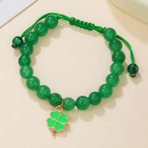 Detail of green beaded bracelet with gold-edged four-leaf clover charm and woven texture
