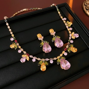 Detailed view of colorful pear-cut pink gems and leaf-shaped crystals on gold necklace