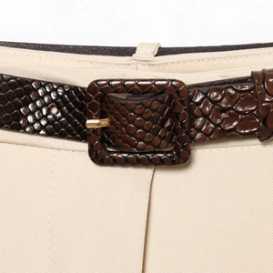 Ceinture marron motif serpent avec boucle carrée sur un pantalon beige court