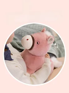 Gros plan d'une peluche de cheval rose doux tenue dans un cadre intérieur chaleureux