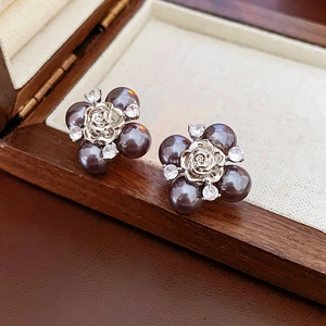 Macro view of dark grey pearl earrings with silver rose flower and zircon in a wood box