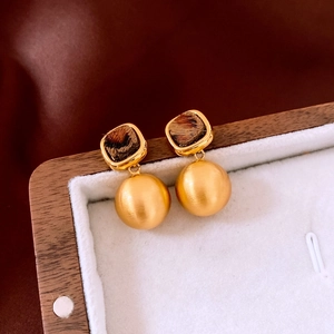 Detail of matte gold ball earrings with leopard print plush texture and square studs
