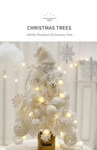 Close-up of white flocked mini Christmas tree with LED lights and handmade ornaments
