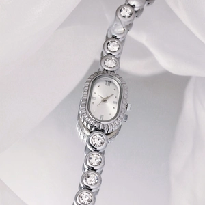 Detail of silver oval vintage watch with radiant textured bezel and rhinestone strap