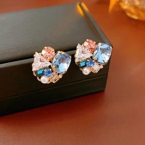 Close-up of cluster earrings with blue crystals and pearls on a black leather box