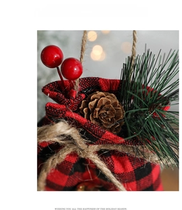 Detail of buffalo check Christmas gift bag with pine cones and festive red berries