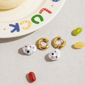 Close-up of gold hoop earrings with baroque pearl drop and colorful gemstone inlays