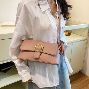 Pink lychee texture leather shoulder bag with gold buckle on a model in a modern interior