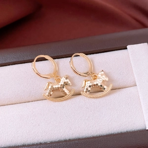 Gros plan de boucles d'oreilles cheval à bascule plaquées or 18 carats sur velours blanc