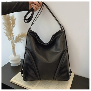 Detail of black soft PU leather hobo bag featuring symmetrical zipper design on desk