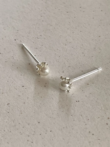Macro shot of 925 sterling silver pearl stud earrings with detailed crown setting