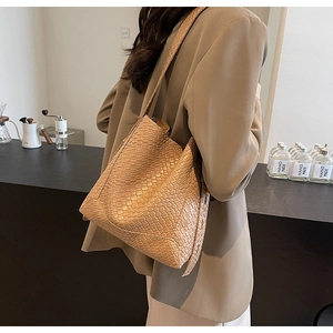 Detail of khaki woven tote bag showing luxury texture and handmade craftsmanship style