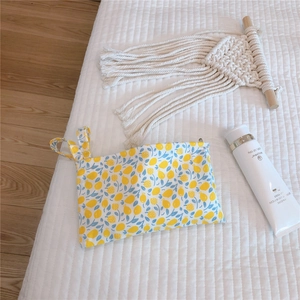 Detailed texture of cotton canvas mini pouch with yellow lemon and blue floral pattern