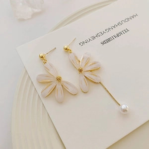 Details von asymmetrischen weißen Blütenohrringen mit langer Goldkette und Perle