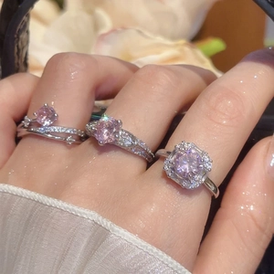 Close-up of silver rings featuring pink zircon in heart, round, and square shapes