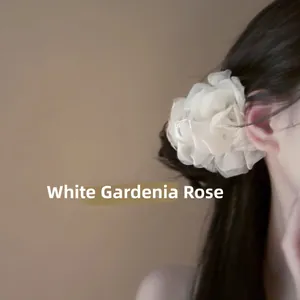 Dettaglio molletta a fiore in tessuto bianco indossata su una coda di cavallo elegante