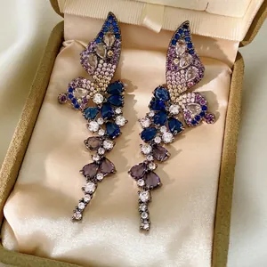 Boucles d'oreilles papillon à pompons avec zircons colorés présentées dans un écrin