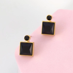 Macro detail of geometric square black gemstone earrings with gold-plated metal frames