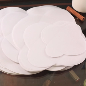 Stack of white petal-shaped parchment paper for wedding invitations on dark wooden desk