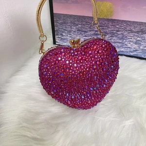 Close-up of pink rhinestone heart-shaped evening bag with golden chain and clasp