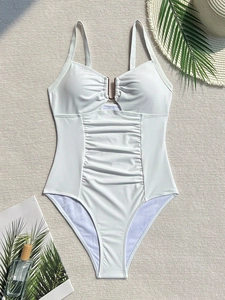 White one-piece swimsuit with U-shaped metal hardware and slimming pleated waist detail