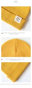 Detail of the yellow ribbed knit baby hat showing the smiley face patch and stitching