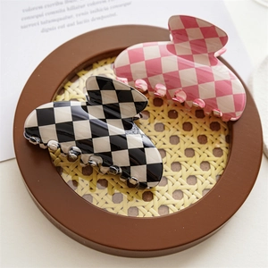 Detailed view of checkered claw clips in black and pink on a woven tray surface