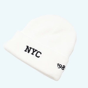 Detail view of the white knitted beanie featuring bold black NYC embroidery and folding cuff