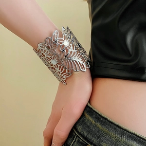 Detailed view of silver hollow floral metal cuff bracelet worn on a model wrist