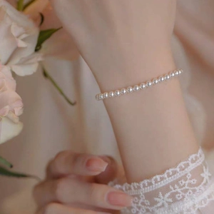 Close-up of elegant white round pearl bracelet worn on wrist with 14k gold clasp detail