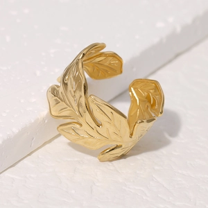 Poliertes Goldblatt-Ring aus Edelstahl, offenes Design auf weißem Stein-Hintergrund