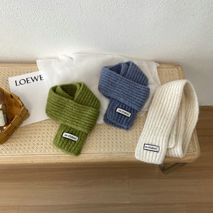 Close-up of knit wool scarves in green, blue, and white with woven KN STUDIO labels