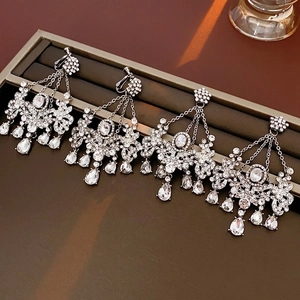 Elegant silver tassel earrings with flower cluster and crystal teardrops on a tray