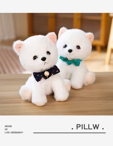 Close-up of white plush puppy toys with polka dot bow ties on a warm wooden surface