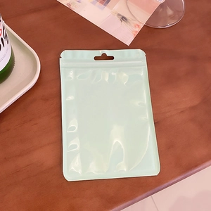 Flat lay of a mint green stand-up pouch with zip closure on a wooden desk
