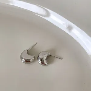 Boucles d'oreilles lune en argent poli présentées dans une coupelle en céramique