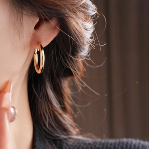 Dettaglio degli orecchini a cerchio dorati minimalisti indossati da una modella elegante