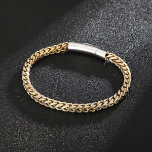 Close-up of gold and silver steel wheat link chain bracelet with cylinder clasp