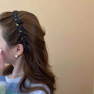 Detail shot of a colorful knitted wave headband paired with elegant pearl earrings