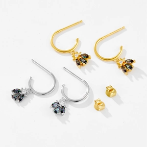 Detail of bee earrings in gold and silver finish with colorful zircon stones on wings