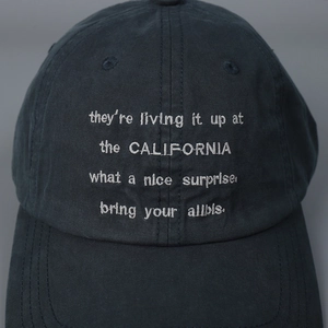Front view of washed cotton baseball cap with white letter embroidery on navy fabric