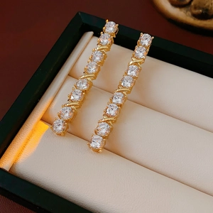 Close-up of golden teardrop earrings with crystals in a beige jewelry box tray