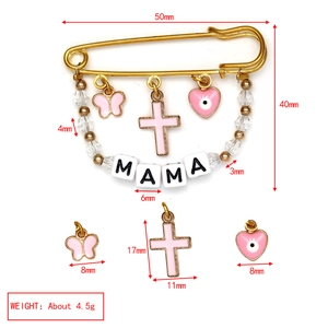 Detail view of a gold evil eye brooch with MAMA beads and pink butterfly charms