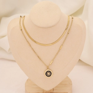 Détail d'un collier double rang doré avec chaîne serpent et pendentif soleil noir sur buste