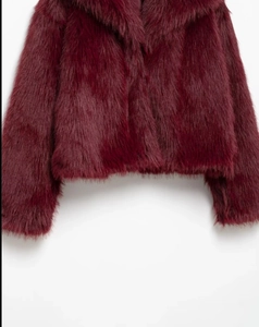 Gros plan sur la texture en fausse fourrure bordeaux de cette veste d'hiver chic