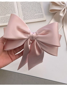Close-up of a large pink satin bow hair clip on an open book for a French aesthetic