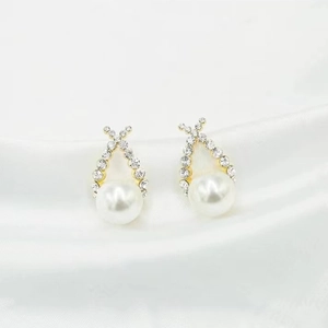 Elegant gold drop earrings with pearl pendants and sparkling zircons on white silk